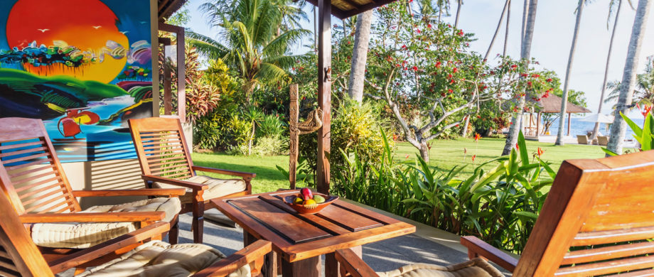 Patio lounge chairs with an ocean view and Balinese art at Villa Joglo at Citakara Sari Estate