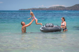 プールのおもちゃで海で泳いでいるバリのチタカラサリエステートで休暇を楽しんでいる家族