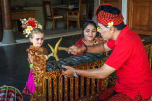 Bambini che indossano costumi balinesi e imparano gli strumenti balinesi mentre sono in vacanza presso la tenuta Citakara Sari