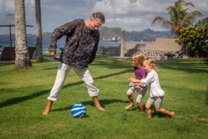 Eine Familie, die Fußball auf den weiten Rasenflächen am Meer des Citakara Sari Estate spielt